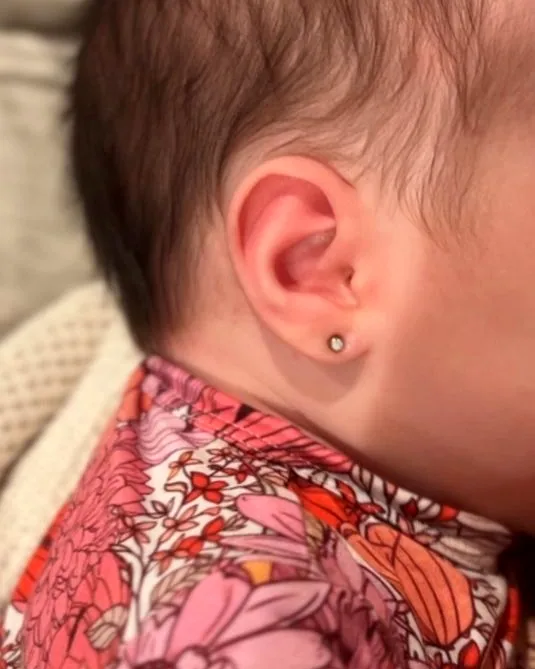A baby's first lobe piercing with a small stud